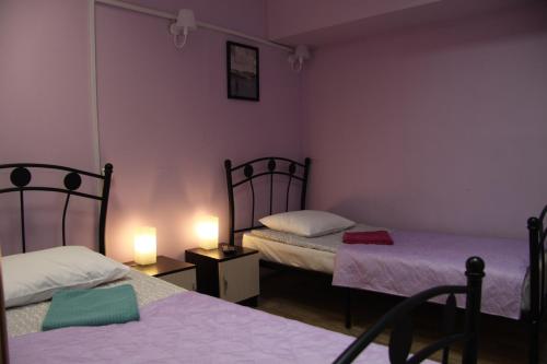 two beds in a room with purple walls and two lamps at Travel Inn Достоевская in Moscow