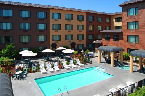 una imagen de una piscina de hotel con sillas y sombrillas en Oxford Suites Chico, en Chico