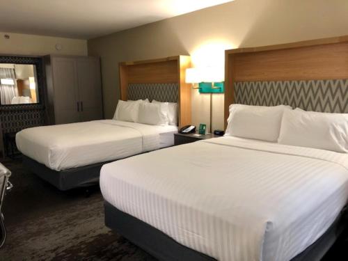a hotel room with two beds with white sheets at Holiday Inn Chicago North Shore by IHG in Skokie