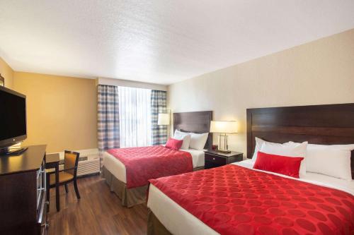 a hotel room with two beds and a flat screen tv at Ramada by Wyndham Venice Hotel Venezia in Venice