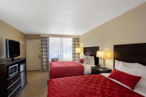 a hotel room with two beds and a flat screen tv at Ramada by Wyndham Venice Hotel Venezia in Venice