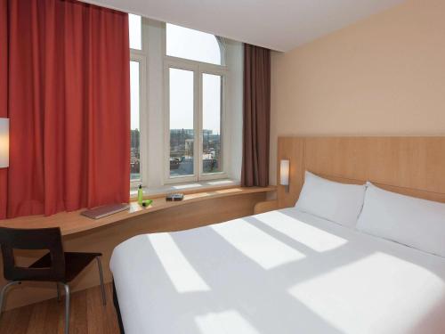 メスにあるibis Metz Centre Gareのベッド、デスク、窓が備わるホテルルームです。