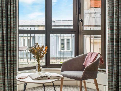 a room with a chair and a table and a window at Mercure Paris Gare Montparnasse in Paris