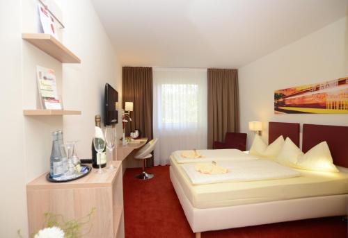 ein Hotelzimmer mit einem Bett und einem Schreibtisch mit einem TV in der Unterkunft Hotel Montana in Diemelstadt 