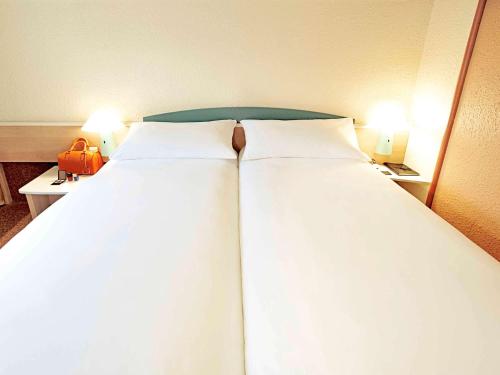 a large bed with two white pillows in a room at ibis Brugge Centrum in Bruges