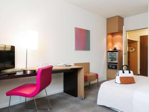 a hotel room with a desk and a bed and a desk and chair at Novotel Frankfurt City in Frankfurt