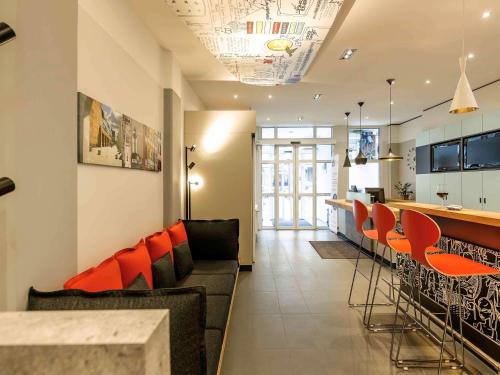 a living room with a bar and orange chairs at ibis Hotel Nürnberg Altstadt in Nuremberg