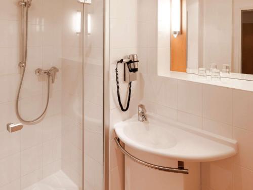 a bathroom with a shower, sink, and mirror at ibis Hotel Nürnberg Altstadt in Nuremberg
