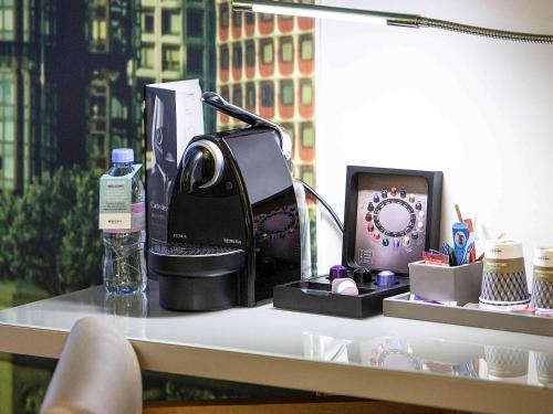 a desk with a coffee maker and a clock on it at Mercure Paris Vaugirard Porte De Versailles in Paris