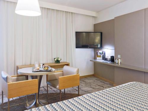 a hotel room with a table and chairs and a television at Mercure Paris Vaugirard Porte De Versailles in Paris