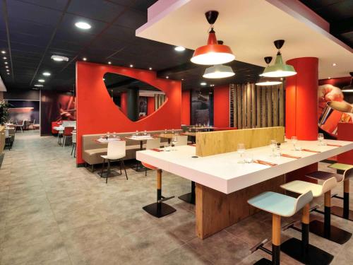 een restaurant met tafels en stoelen en een rode muur bij ibis Lille Centre Gares in Lille