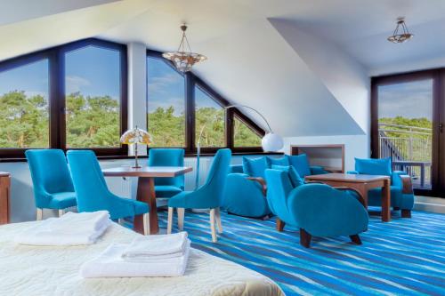 a hotel room with blue chairs and tables and windows at Hotel Willa Złota in Karwia
