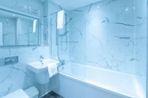 a bathroom with a sink and a tub and a toilet at Stunning 2 Bed Merchant City Apartment with Residents Parking (Bell 2) in Glasgow