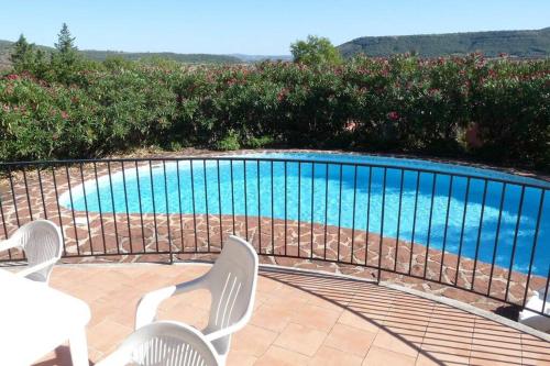 - une piscine avec 2 chaises blanches et une table dans l'établissement La Bergerie, with private pool and garden, à Lodève