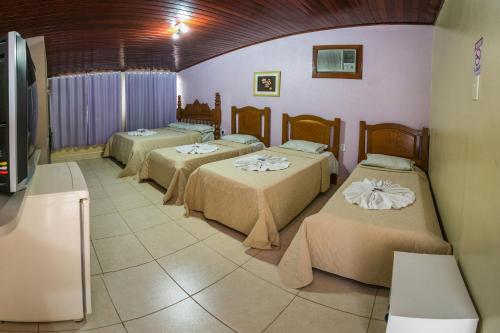 a group of three beds in a room at Pousada Bom Jardim in Chapada dos Guimarães