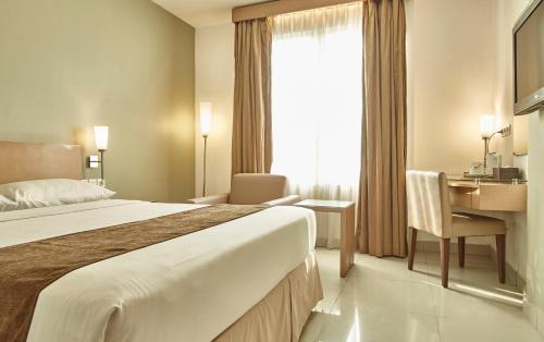 a hotel room with a large bed and a desk at Triniti Hotel Jakarta in Jakarta