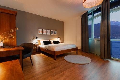 a bedroom with a bed and a desk and window at Hotel Esplanade in Gmunden