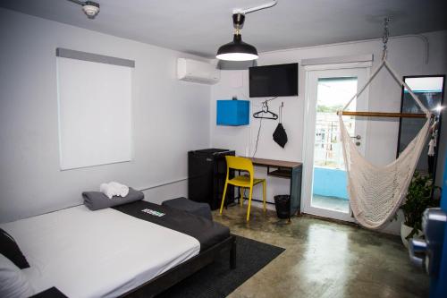 Schlafzimmer mit einem Bett, einem Schreibtisch und einer Hängematte in der Unterkunft Nomada Urban Beach Hostel- Calle Loiza in San Juan