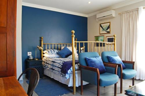 克拉倫斯的住宿－Stonehaven Clarens，一间卧室配有一张蓝色墙壁的床和两把椅子