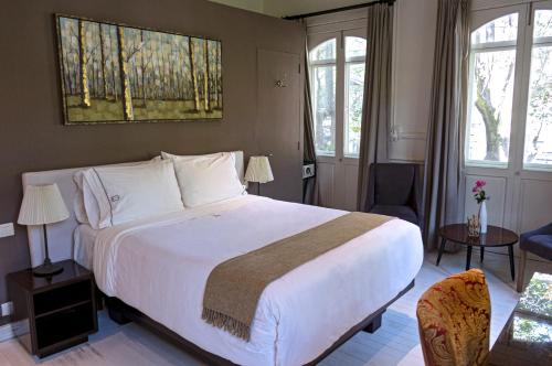 a bedroom with a large white bed and two windows at Hotel Villa Condesa in Mexico City