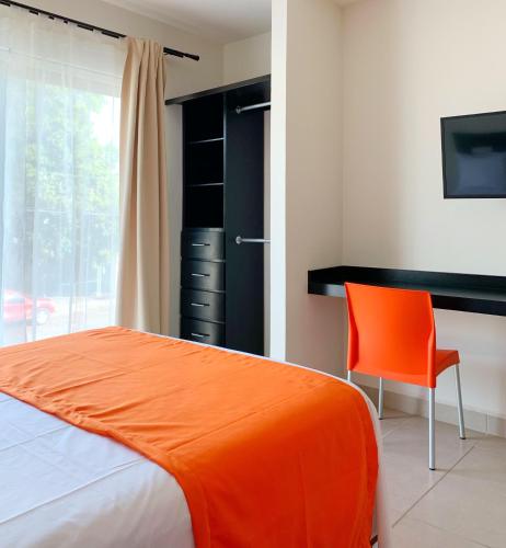 - une chambre avec un lit orange et une chaise dans l'établissement Hotel Diez, à Tampico