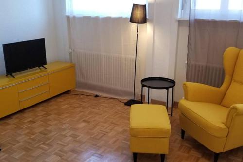 a living room with a yellow chair and a tv at HSH Barre 6 - City Apartment next Cathedral Lausanne in Lausanne