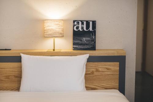 a bed with a white pillow and a lamp at Hotel Noum OSAKA in Osaka