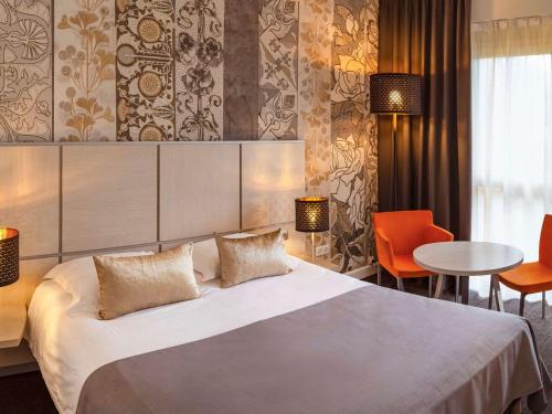 Habitación de hotel con cama, mesa y sillas en Mercure Bourg En Bresse en Bourg-en-Bresse