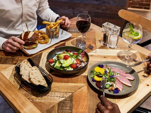 a table with plates of food and glasses of wine at Novotel Wolverhampton City Centre in Wolverhampton