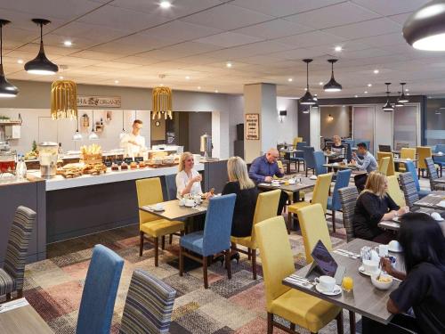 a group of people sitting at tables in a restaurant at Novotel Wolverhampton City Centre in Wolverhampton