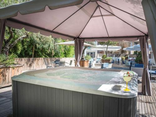 a hot tub with an umbrella and a drink in it at Mercure Ajaccio in Ajaccio