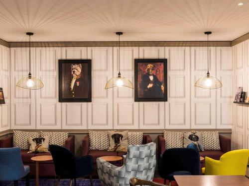 un restaurant avec des chaises et des portraits sur le mur dans l'établissement Mercure Paris Roissy CDG, à Roissy-en-France