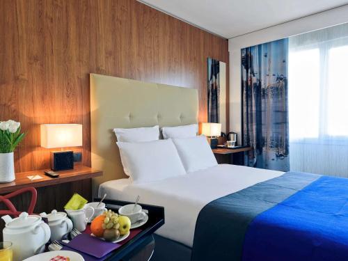 尼斯的住宿－尼斯城中心聖母院美居酒店，酒店客房设有一张大床和一张带水果的桌子。