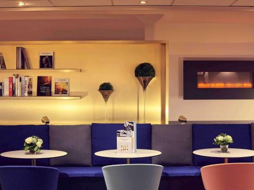 a restaurant with two tables and a blue couch at Mercure Rouen Centre Cathédrale in Rouen