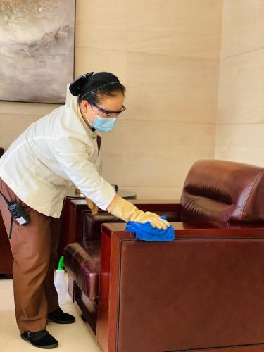 a man wearing a mask and gloves cleaning a desk at Springdale Serviced Residence Guangzhou in Guangzhou