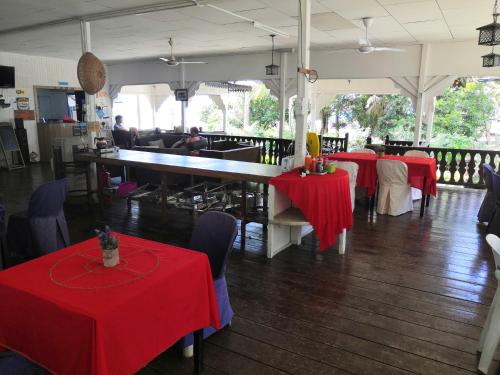 a restaurant with red tables and chairs and a counter at Impian Inn in Tioman Island