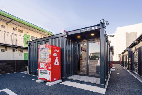 a black building with a red vending machine in front of it at HOTEL R9 The Yard Togane in Tōgane