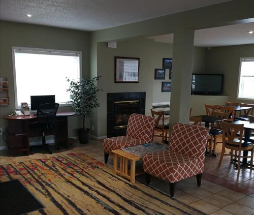 a living room with chairs and a table and a fireplace at Grand Forks Inn in Grand Forks