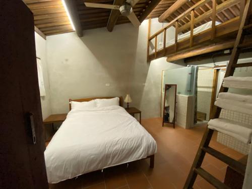 Un dormitorio con una cama blanca y una escalera en House by the Well 總兵人家, en Jincheng