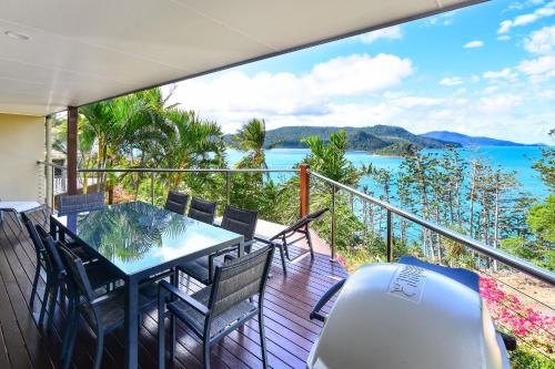a balcony with a table and chairs and a view of the ocean at Cooinda Gardens on Hamilton Island by HIHA in Hamilton Island