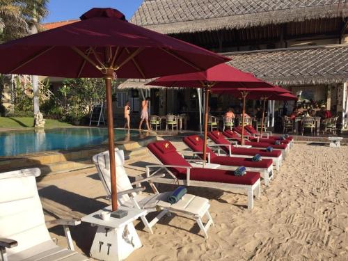 a row of lounge chairs and umbrellas on a beach at Tauch Terminal Resort Tulamben & Spa in Tulamben