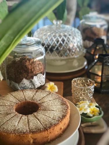 a table with a cake on a plate next to jars at Tauch Terminal Resort Tulamben & Spa in Tulamben