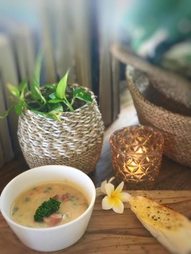 a bowl of soup and flowers on a wooden table at Tauch Terminal Resort Tulamben & Spa in Tulamben