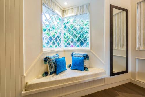 asiento junto a la ventana en una habitación con almohadas azules en amã Stays & Trails, Beach House Madh Island, en Bombay