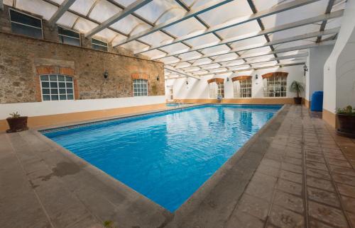 an indoor swimming pool with a glass ceiling at Hacienda Soltepec Suites Campo de Golf in Huamantla