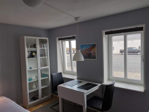 a bedroom with a desk and two windows at Vestbjerg Apartments in Vestbjerg