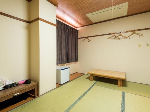 an empty room with a table and a bench at Tabist Hotel Kurama Hikone in Takamiya