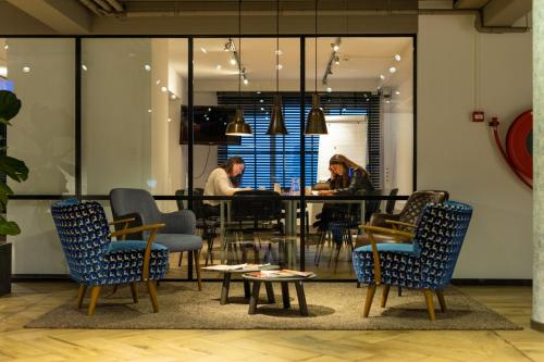 a group of people sitting at a table in a room at Skotel The Hague, Hotelschool The Hague in Scheveningen