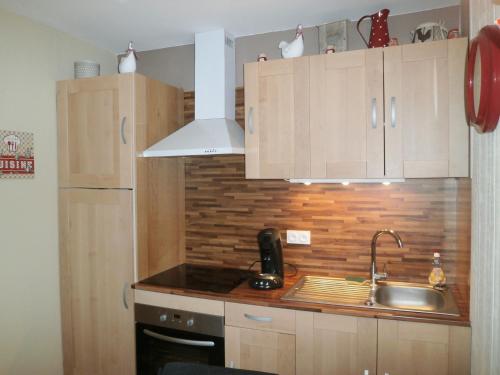 a kitchen with wooden cabinets and a sink at Au 14 Honfleur parking privé in Honfleur