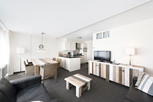 a living room with a couch and a table at WestCord Strandhotel Seeduyn in Oost-Vlieland